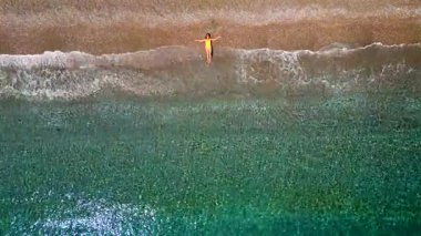 Sörf hattında kumlu bir plajda uzanan sarı mayo giymiş bir kızın yukarıdan görünüşü. Yunanistan 'ın Rodos Adasının kıyısında. Yaz tatilleri.