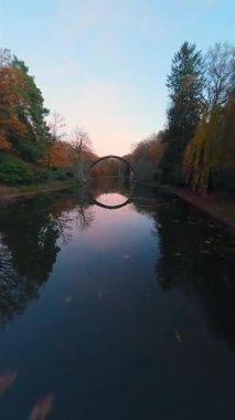 Devils Köprüsü Rakotzbrucke Rhododendron Sarayı Parkı Kromlau, Rakotz Gölü, Saksonya, Almanya. Su yüzeyinde FPV uçuşu. Dikey video