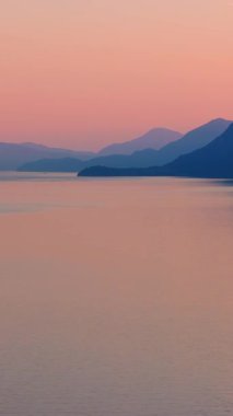 Akşamları Vancouver 'ın kuzeyindeki deniz manzarası. Pembe gökyüzü ve dağların siluetleri. British Columbia, Kanada.