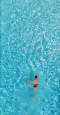 Kırmızı şortlu bir adam havuzda yüzüyor. Yaz yaşam tarzı. Yavaş çekim