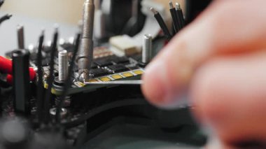 İHA kontrol panelinde lehimleme için hazırlanan bir kabloyu aşırı yakın çekim makro görüntüsü. Fpv insansız hava aracının mikroçipindeki lehimleme bağlantıları süreci.