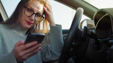 Arabada beklerken akıllı telefon kullanan mutlu güzel bir kadının portresi. Yavaş çekim