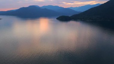 Akşamları Vancouver 'ın kuzeyindeki deniz manzarası. Mavi bulutlu gökyüzü ve dağların siluetleri. British Columbia, Kanada.