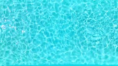 Yüzme havuzundaki saf mavi suyun yüzeyinde ışık yansımaları var. Hava görüntüleri, yukarıdan aşağı görünüm. 