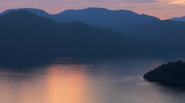 Akşamları Vancouver 'ın kuzeyindeki deniz manzarası. Mavi bulutlu gökyüzü ve dağların siluetleri. British Columbia, Kanada.
