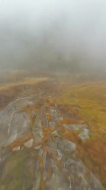 Mistik sonbahar manzarası. FPV dronu, suyun aktığı taş yüzeyin yakınındaki siste hızla uçar. Malta, Avusturya. Dikey video