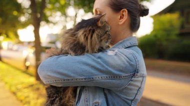 Dışarıda tekir kedisini kucaklayan güzel bir kadın. Kedi miyavlamaları