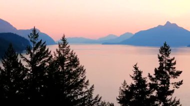 Akşamları Vancouver 'ın kuzeyindeki deniz manzarası. Pembe gökyüzü ve dağların siluetleri. British Columbia, Kanada.