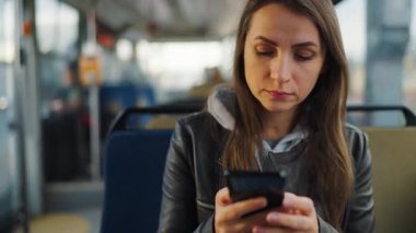 Public transport. Woman in tram using smartphone chatting and texting with friends. City, urban, transportation.