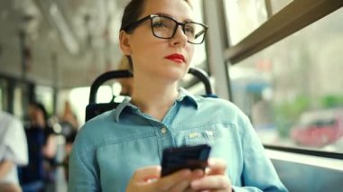Toplu taşıma. Tramvaydaki gözlüklü kadın akıllı telefon konuşmaları yapıyor ve arkadaşlarıyla mesajlaşıyor. Şehir, şehir, ulaşım.