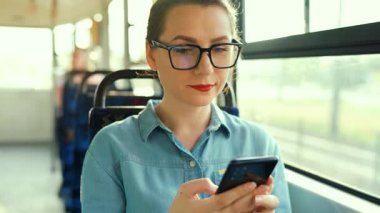 Toplu taşıma. Tramvaydaki gözlüklü kadın akıllı telefon konuşmaları yapıyor ve arkadaşlarıyla mesajlaşıyor. Şehir, şehir, ulaşım. Yavaş çekim