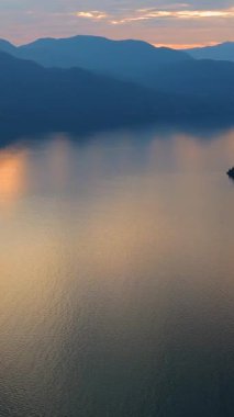 Akşamları Vancouver 'ın kuzeyindeki deniz manzarası. Gün batımı bulutlu gökyüzü ve dağların siluetleri. British Columbia, Kanada.