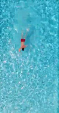 Kırmızı şortlu bir adam havuzda yüzüyor. Yaz yaşam tarzı.