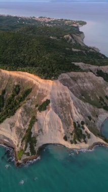 Yunanistan 'daki Korfu adasındaki sahil şeridinin havadan görüntüsü. Gün batımında güzel deniz manzarası. Dikey video