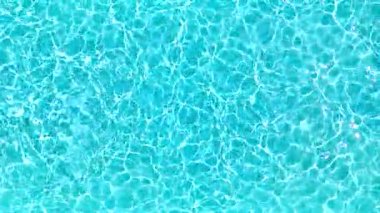 Yüzme havuzundaki saf mavi suyun yüzeyinde ışık yansımaları var. Hava görüntüleri, yukarıdan aşağı görünüm. 