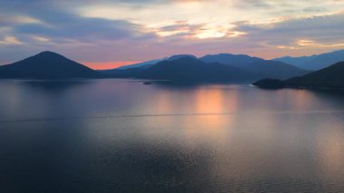 Akşamları Vancouver 'ın kuzeyindeki deniz manzarası. Mavi bulutlu gökyüzü ve dağların siluetleri. British Columbia, Kanada.