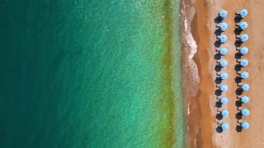 Mavi güneş şemsiyeleri ve turkuaz deniz suyuyla cennet gibi kumlu sahil manzarası.. 