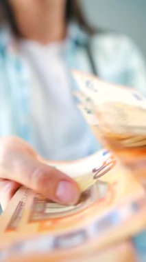 Avro banknotlarını sayan bir kadın, yakın plan. Yatırım, başarı, finansal beklentiler veya kariyer gelişimi kavramı. Dikey video