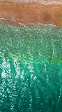 Yukarıdan aşağıya çakıl taşı plajı ve kristal berrak su görüntüsü. Rodos, Yunanistan. Dikey video. Yavaş çekim