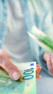 Avro banknotlarını sayan bir kadın, yakın plan. Yatırım, başarı, finansal beklentiler veya kariyer gelişimi kavramı. Dikey video