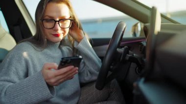 Arabada beklerken akıllı telefon kullanan mutlu güzel bir kadının portresi. Yavaş çekim