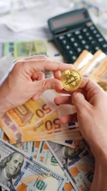 Erkek eli, BTC bitcoin 'i farklı para birimlerinin banknotları olan dolar ve avrolar ile karşılaştırır ve döndürür. Kripto para birimi kavramı ve engelleme teknolojisinin geniş dünyası..