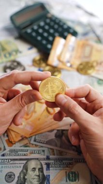 Erkek eli, farklı para birimlerinin -dolar ve avro- arka planında BTC bitcoin gösteriyor. Kripto para birimi kavramı ve engelleme teknolojisinin geniş dünyası..