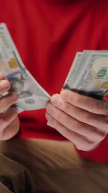 ABD Doları banknotlarını sayan adam, yakın plan. Yatırım, başarı, finansal beklentiler veya kariyer gelişimi kavramı. Dikey video