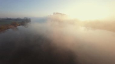 Polonya 'nın Tyniec kentindeki Vistula Nehri ve Benedictine Manastırı' nın alışılmadık hava manzarası. Güneş ışınları sabah sisinin içinden geçiyor. Katolik manastırı ve çevresindeki manzaranın eski mimarisi. Kaydedildi