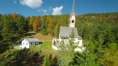 St. Jacob Kilisesi 'nin havadan görünüşü, arka planda Ortisei kasabasının yanındaki San Giacomo Kilisesi Langkofel grubunun dağları FPV insansız hava aracı ile filme alındı. Bolzano ili