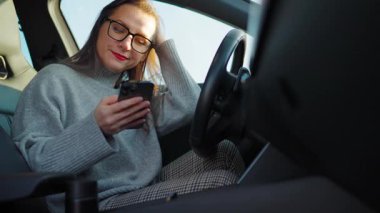 Arabada beklerken akıllı telefon kullanan mutlu güzel bir kadının portresi. Yavaş çekim