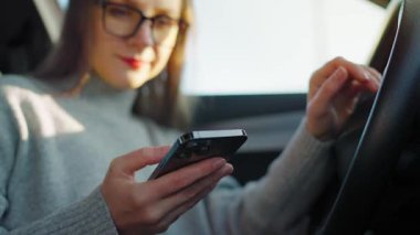 Arabada beklerken akıllı telefon kullanan mutlu bir kadının portresi.. 