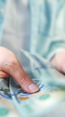 Amerikan Doları 'nı sayan bir kadın, yakın plan. Yatırım, başarı, finansal beklentiler veya kariyer gelişimi kavramı. Dikey video