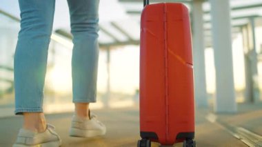 Bir gezgin gün batımında şık kahverengi bavullarıyla havaalanı terminalinde rahatça dolaşır. Yaz tatili kavramı. Ağır çekim. Arka görünüm