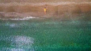 Sörf hattında kumlu bir plajda uzanan sarı mayo giymiş bir kızın yukarıdan görünüşü. Yunanistan 'ın Rodos Adasının kıyısında. Yaz tatilleri.