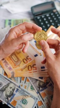 Erkek eli, BTC bitcoin 'i farklı para birimlerinin banknotları olan dolar ve avrolar ile karşılaştırır ve döndürür. Kripto para birimi kavramı ve engelleme teknolojisinin geniş dünyası..