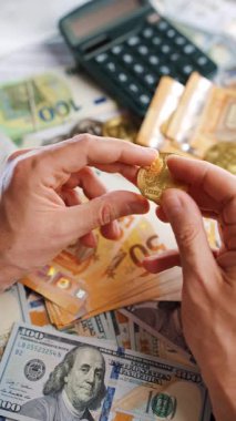 Erkek eli, BTC bitcoin 'i farklı para birimlerinin banknotları olan dolar ve avrolar ile karşılaştırır ve döndürür. Kripto para birimi kavramı ve engelleme teknolojisinin geniş dünyası..