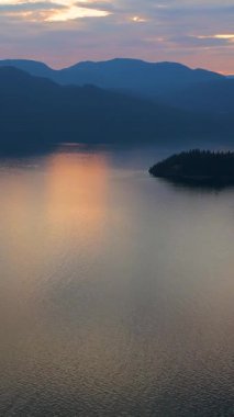 Akşamları Vancouver 'ın kuzeyindeki deniz manzarası. Gün batımı bulutlu gökyüzü ve dağların siluetleri. British Columbia, Kanada.