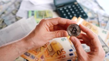 Erkek eli, farklı para birimlerinin -dolar ve avro- arka planında BTC bitcoin gösteriyor. Kripto para birimi kavramı ve engelleme teknolojisinin geniş dünyası..