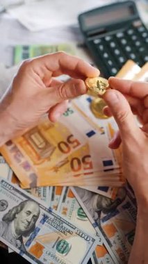 Erkek eli, BTC bitcoin 'i farklı para birimlerinin banknotları olan dolar ve avrolar ile karşılaştırır ve döndürür. Kripto para birimi kavramı ve engelleme teknolojisinin geniş dünyası..