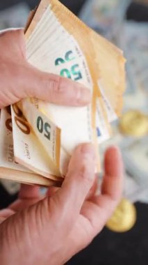 Avro banknotlarını sayan erkek eller. Arka planda Amerikan doları banknotları var. Yatırım, başarı, finansal beklentiler veya kariyer ilerlemesi kavramı.