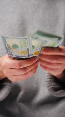 Amerikan Doları 'nı sayan bir kadın, yakın plan. Yatırım, başarı, finansal beklentiler veya kariyer gelişimi kavramı. Dikey video