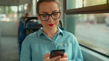 Toplu taşıma. Tramvaydaki gözlüklü kadın akıllı telefon konuşmaları yapıyor ve arkadaşlarıyla mesajlaşıyor. Şehir, şehir, ulaşım. Yavaş çekim