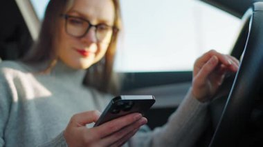 Arabada beklerken akıllı telefon kullanan mutlu güzel bir kadının portresi. Yavaş çekim