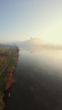 Polonya 'nın Tyniec kentindeki Vistula Nehri ve Benedictine Manastırı' nın alışılmadık hava manzarası. Güneş ışınları sabah sisinin içinden geçiyor. Katolik manastırı ve çevresindeki manzaranın eski mimarisi. Kaydedildi