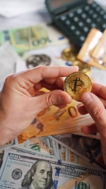 Erkek eli, farklı para birimlerinin -dolar ve avro- arka planında gümüş ve altın BTC bitcoin gösteriyor. Kripto para birimi kavramı ve engin blok zinciri dünyası.