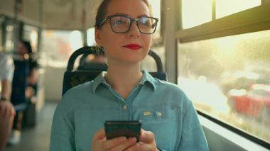 Toplu taşıma. Tramvaydaki gözlüklü kadın akıllı telefon konuşmaları yapıyor ve arkadaşlarıyla mesajlaşıyor. Şehir, şehir, ulaşım. Yavaş çekim