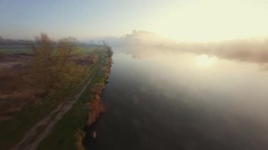 Polonya 'nın Tyniec kentindeki Vistula Nehri ve Benedictine Manastırı' nın alışılmadık hava manzarası. Güneş ışınları sabah sisinin içinden geçiyor. Katolik manastırı ve çevresindeki manzaranın eski mimarisi. Kaydedildi