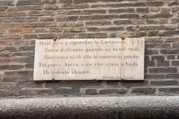 Memorial plaque on the wall of the Garisenda Tower with a quote from Dante\'s poem Inferno dedicated to it. Bologna, Italy