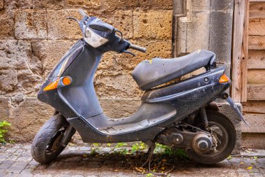 Eski bina duvarının dışına park edilmiş eski model scooter. İtalya